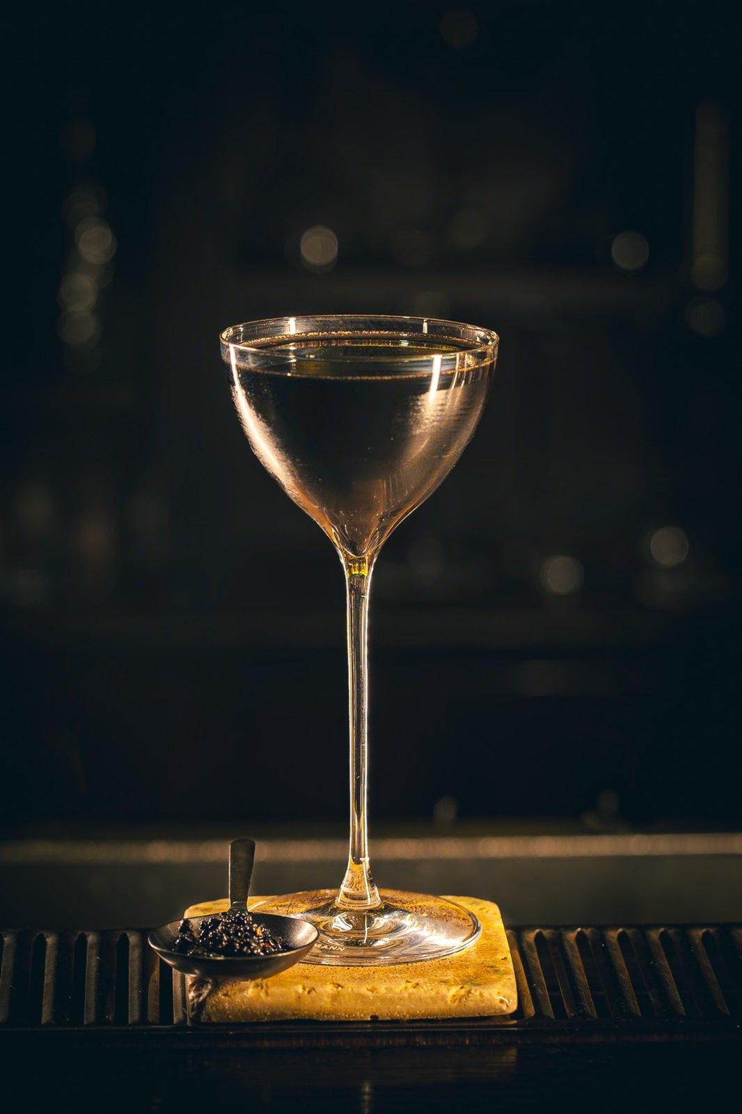 Un verre à cocktail fin et élégant, posé sur un bloc de glace au comptoir